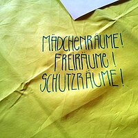 Auf einem zerknitterten Grund sind hier die W&ouml;rter M&auml;dchenr&auml;ume, Freir&auml;ume, Schutzr&auml;ume untereinander geschrieben, in Gro&szlig;buchstaben  und mit Ausrufezeichen versehen. 