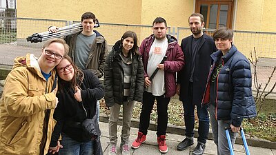 Auf dem Bild sieht man eine Gruppe von Jugendlichen mit Kameraequipment vor einem Haus