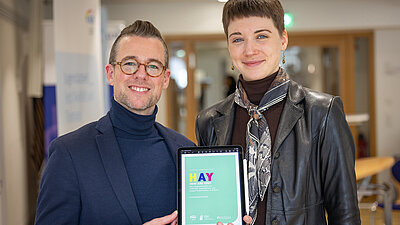 Zwei Personen stehend mit der HAY-Studie auf dem Tablet in der Hand