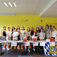 Sch&uuml;ler:innen die hinter Verkaufstischen stehen und Essen verkaufen