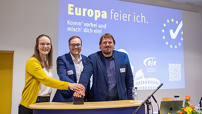 Drei Personen dr&uuml;cken auf einen Buzzer