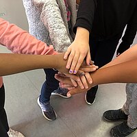 Eine Gruppe Jugendlicher legt ihre H&auml;nde &uuml;bereinander