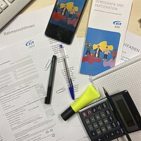 Unterlagen, Flyer und B&uuml;romaterial liegen auf einem Schreibtisch 
