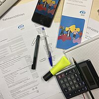 Unterlagen, Flyer und B&uuml;romaterial liegen auf einem Schreibtisch 