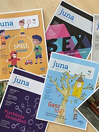 Mehrere juna-Zeitschriften liegen kreuz und quer &uuml;bereinander.