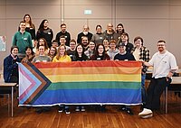 Teilnehmer des Fachtages "Jugendarbeit verqueeren" halten die LGBTQ-Flagge hoch