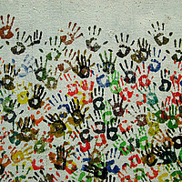 Auf einer Wand sind viele verschiedene bunte Handabdr&uuml;cke