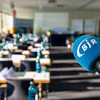 Einblaues Mikrofon mit BJR Logo schwenkt in einen leeren Raum
