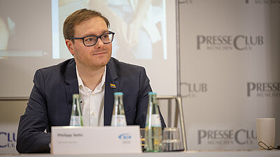 Eine Person sitzend bei der Pressekonferenz