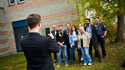 Eine Person beim Gruppenbild mit dem Handy